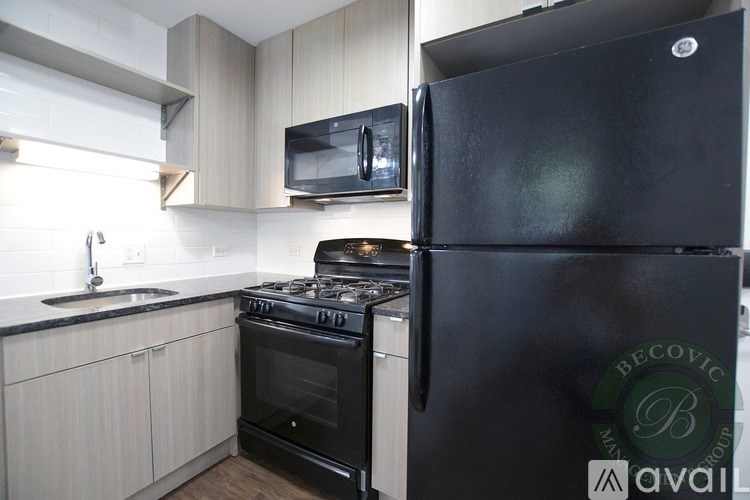 A black fridge in a kitchen with a stove and a microwave above it.