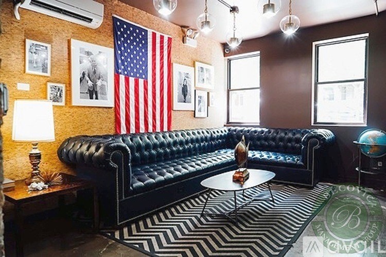 A black and white striped rug is on the floor of a room with a black leather couch.