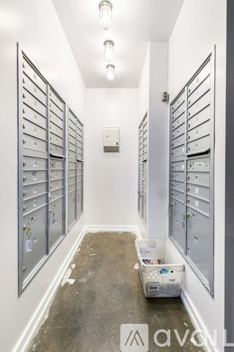 A long hallway with a row of mailboxes on either side and a trash bin in the middle.