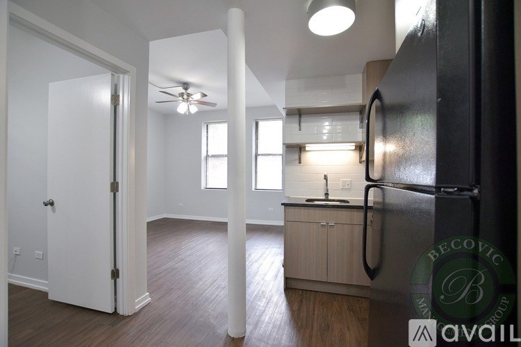 A kitchen with a refrigerator, sink, and cabinets.