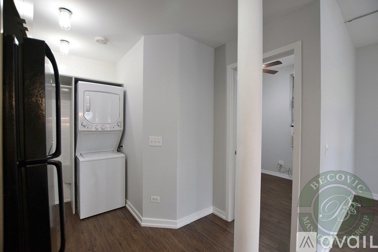 A kitchen area with a black fridge, white dishwasher and a white washing machine.