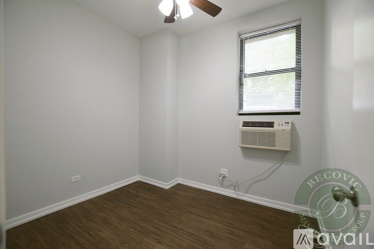 A room with a window and a fan on the ceiling.