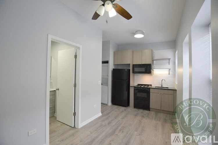 A modern kitchen with a black refrigerator, microwave, and oven, and a ceiling fan.
