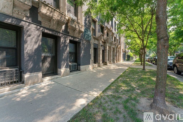 A tree stands on a sidewalk in front of a building.