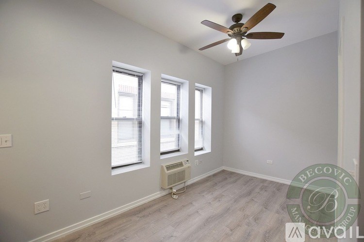 A room with a ceiling fan and two windows.