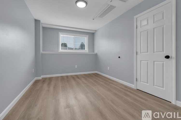 A room with a white door and a window with a view of buildings outside.