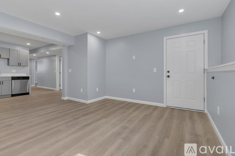 A spacious room with light wood flooring and a white door.