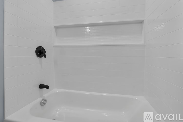 A white bathroom with a tub and a shower head.