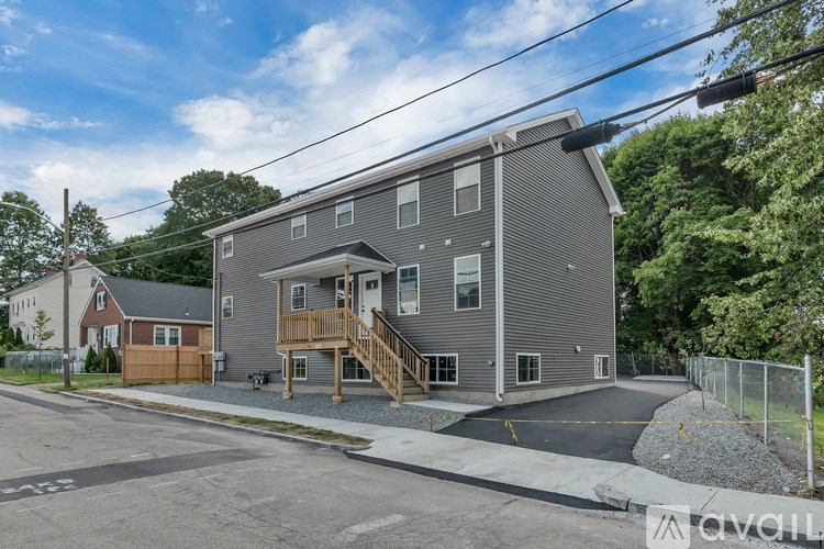 A grey two-story apartment building with a wooden deck on the second floor.