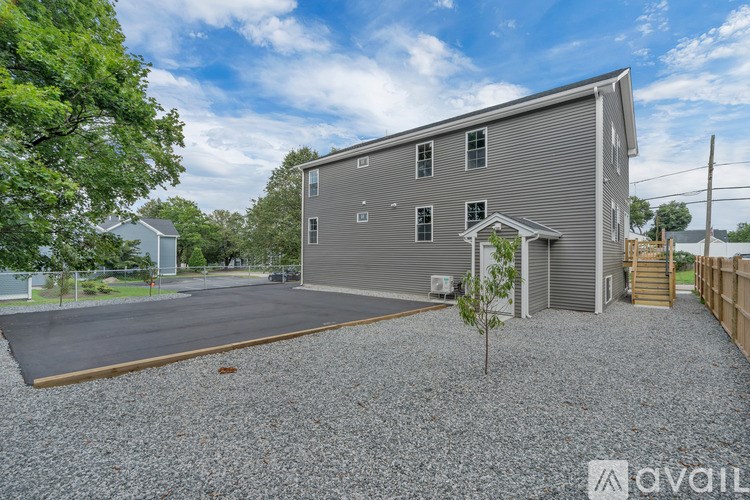A grey building with a gravel driveway in front.
