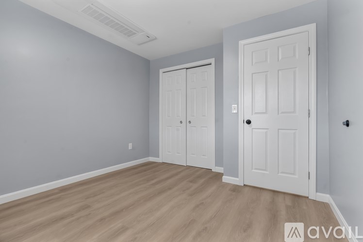 A room with two white doors and a wooden floor.