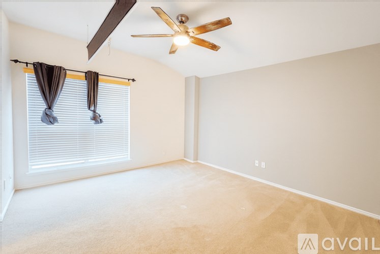 A room with a ceiling fan and a window with curtains.
