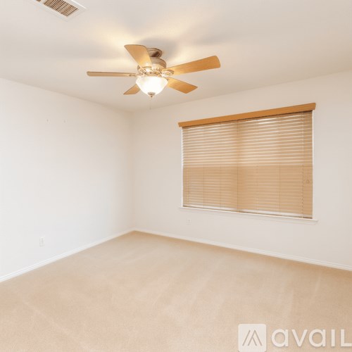 A room with a ceiling fan and a window with blinds.
