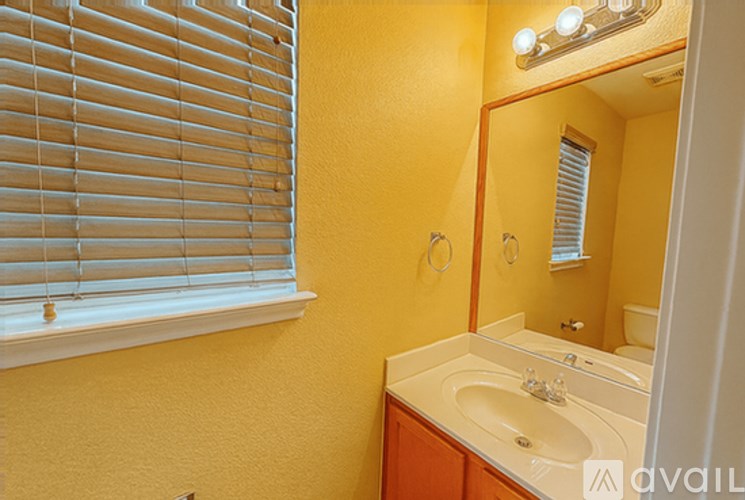 A bathroom with a sink, mirror, and window with blinds.