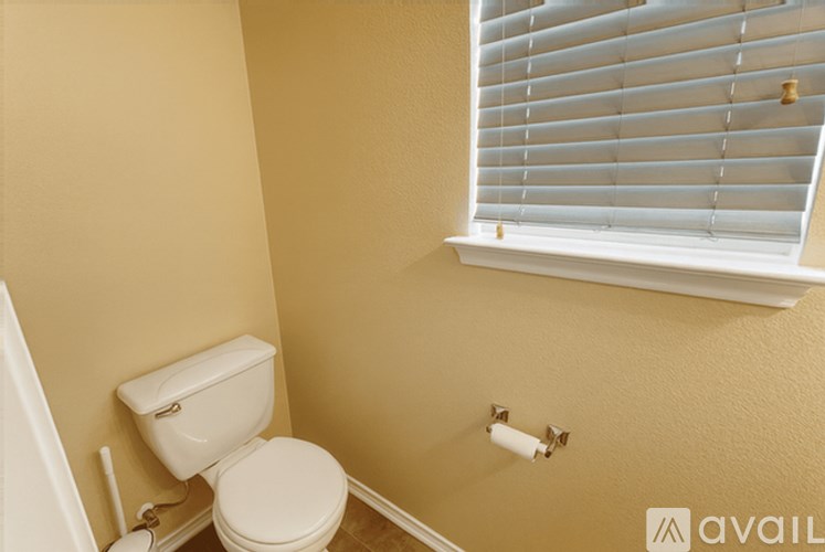 A white toilet in a small bathroom with a window.