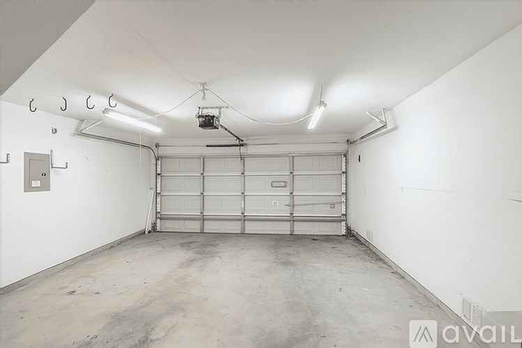 A large, empty garage with a metal door and a hanging light fixture.