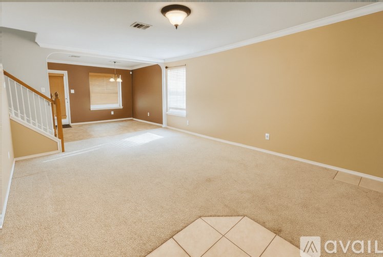A spacious room with beige walls and a carpeted floor.