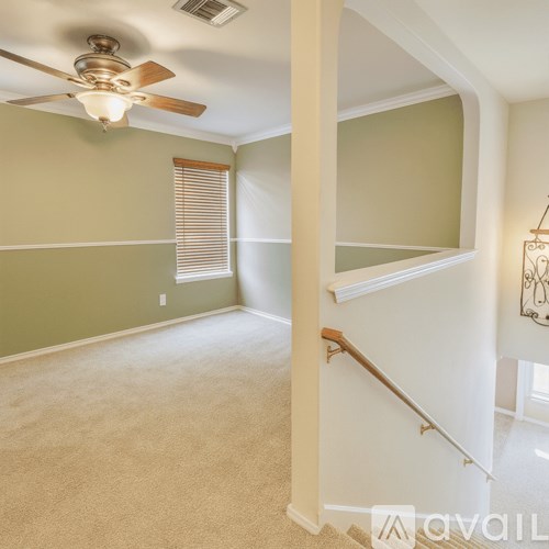 A room with a ceiling fan and a staircase.