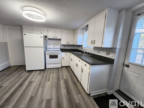 A kitchen with white cabinets and a wooden floor.