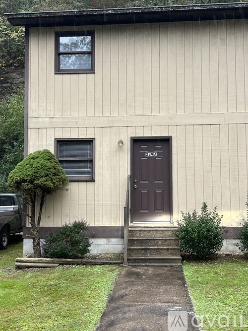 A house with a brown door and a small tree in front.