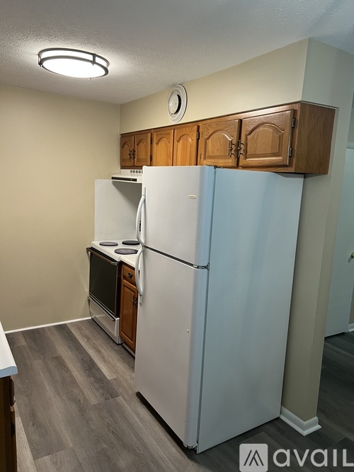 A white refrigerator in a kitchen with wooden cabinets.