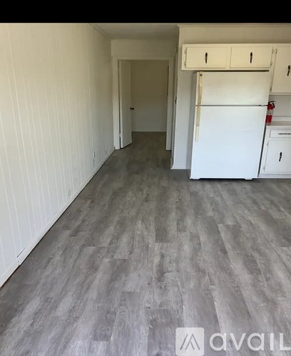 A kitchen area with a white fridge and cabinets.