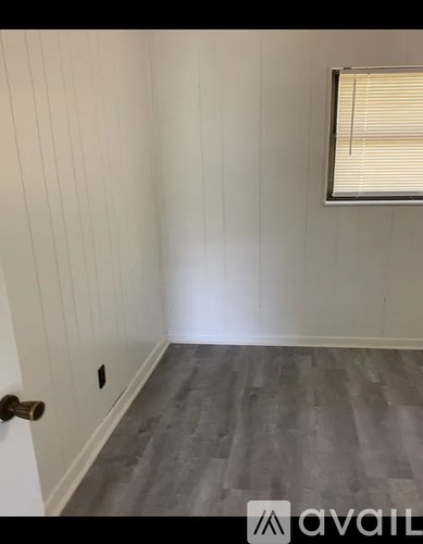 A room with a wooden floor and a window with blinds.