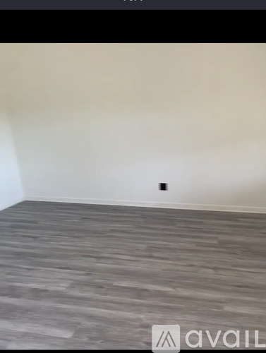 A room with a wooden floor and a wall socket.