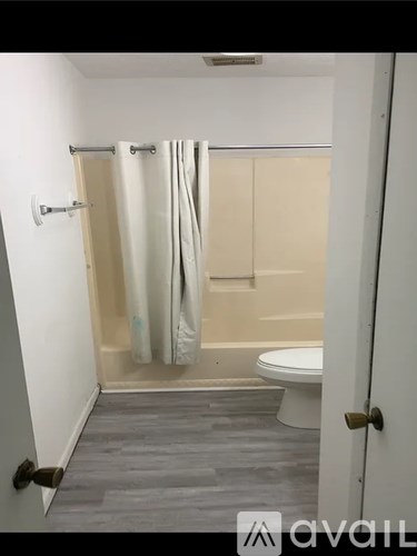 A bathroom with a toilet, a shower curtain, and a towel rack.