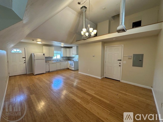 A spacious kitchen and living room with hardwood floors and a high ceiling.