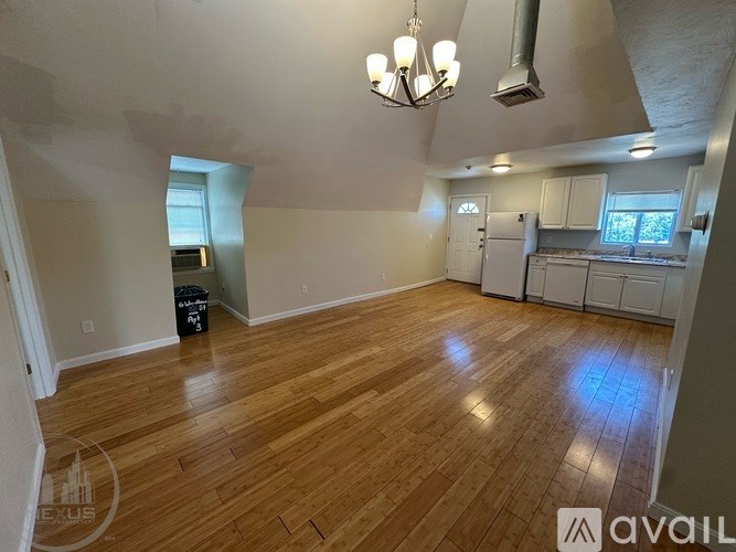 A room with wooden flooring and a chandelier hanging from the ceiling.