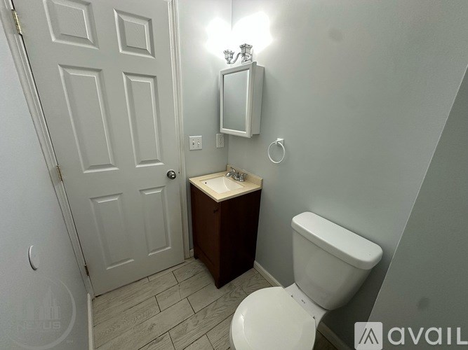 A bathroom with a toilet, sink, and mirror.