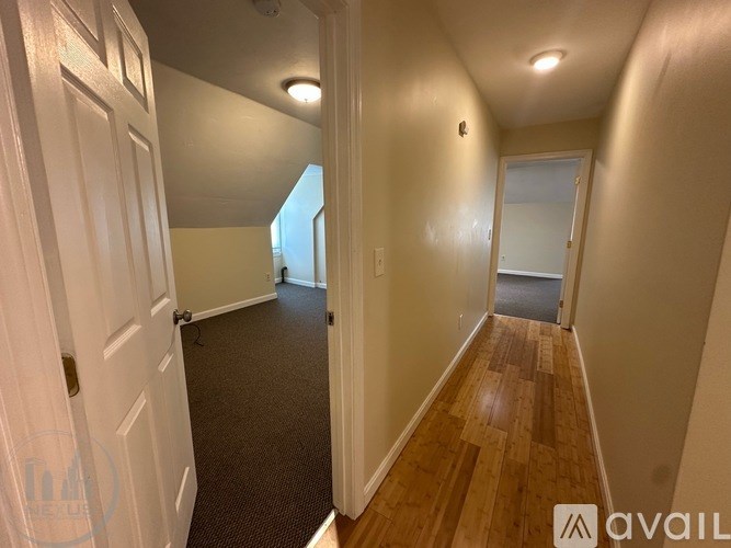 A hallway with wooden floors and white walls.