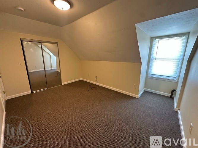 A room with a carpeted floor and a window with blinds.