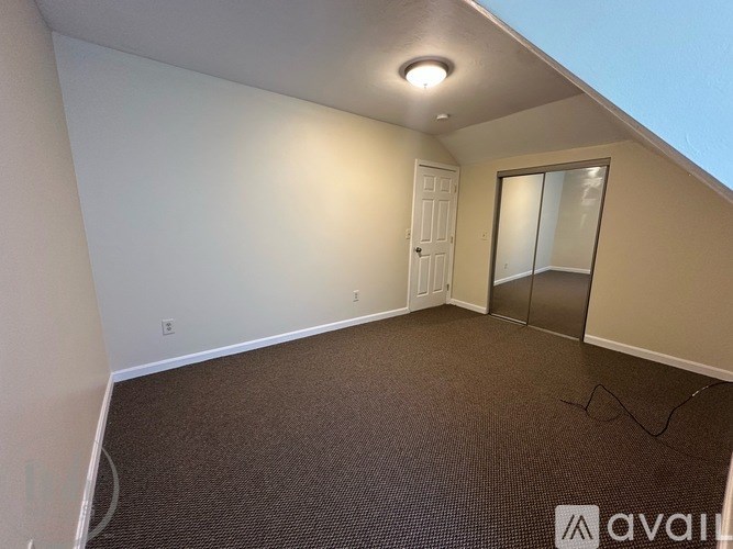 A room with a carpeted floor, a door, and a window.
