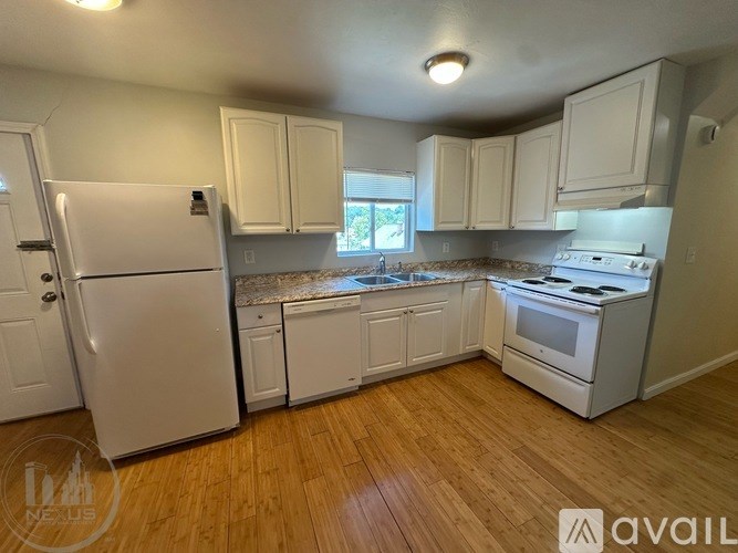 A kitchen with white appliances and wooden floors.
