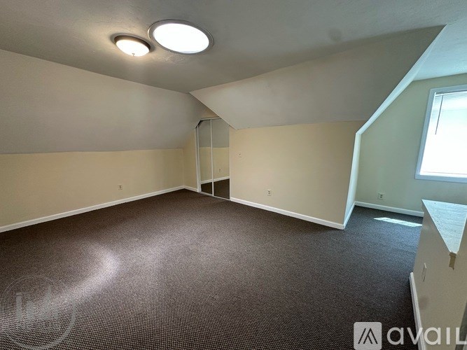 A spacious room with a carpeted floor and a window.