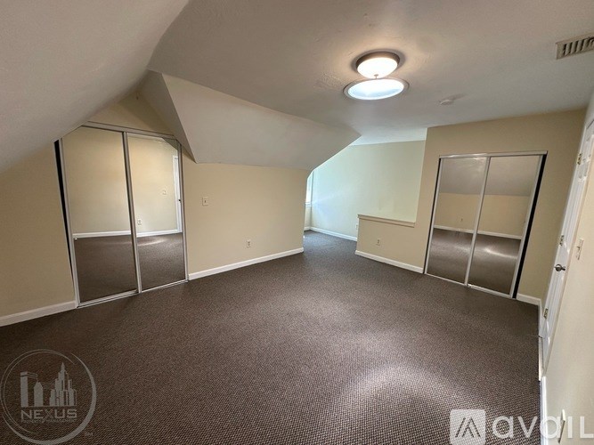 A carpeted room with a skylight and a door on the right.