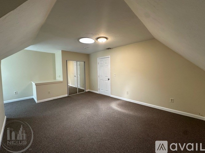 A spacious room with a carpeted floor and a door on the right side.