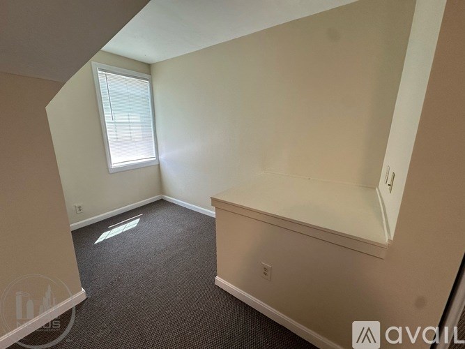 A room with a window and a carpeted floor.