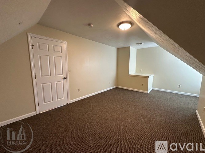 A carpeted room with a door and a window.
