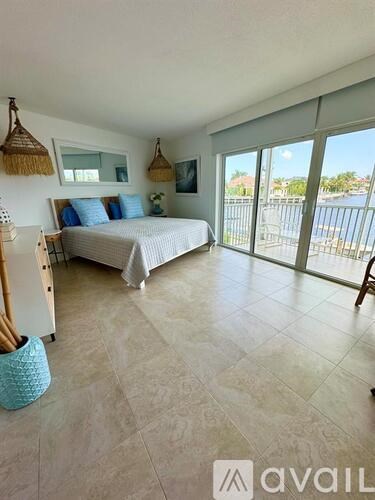A bedroom with a large bed and a balcony overlooking a pool.