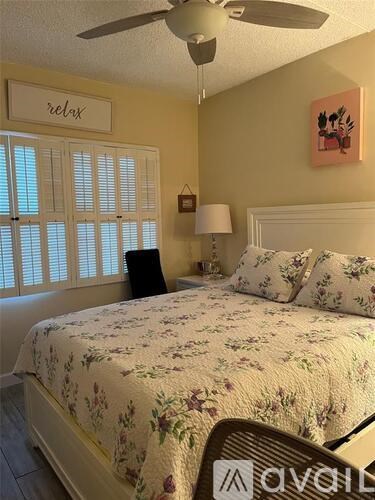 A bedroom with a floral bedspread and a ceiling fan.