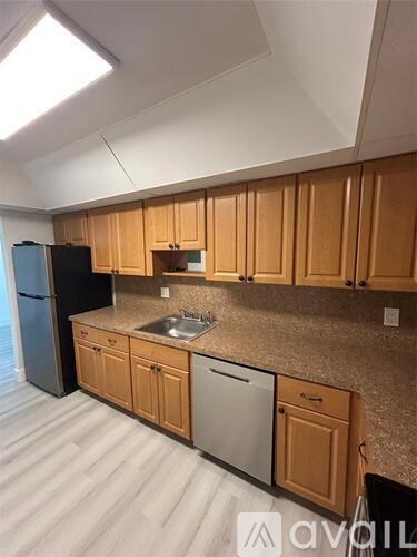 A kitchen with wooden cabinets and a black refrigerator.
