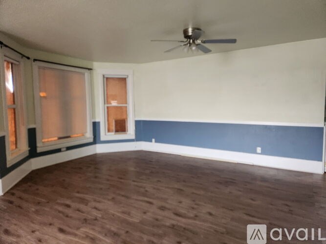 A room with a ceiling fan and wooden flooring.