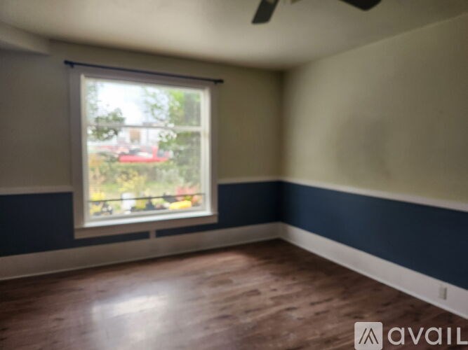 A room with a window and a wooden floor.
