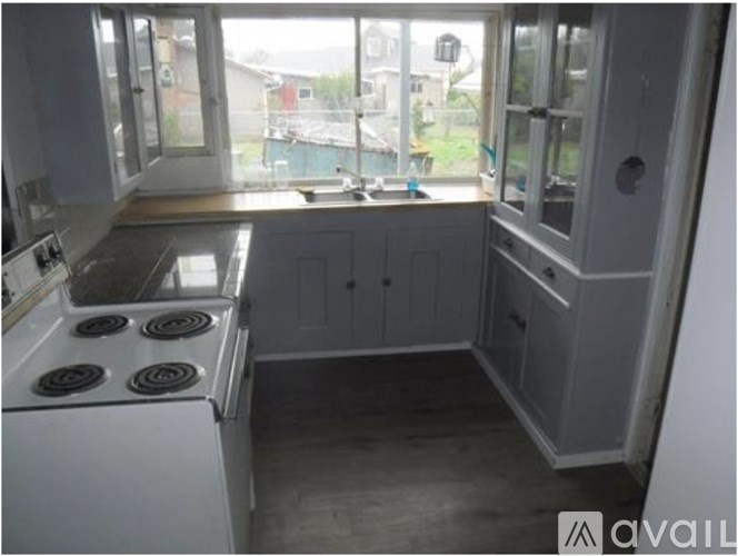 A kitchen with a white stove and cabinets.