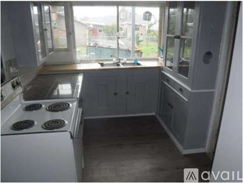 A kitchen with a white stove and cabinets.