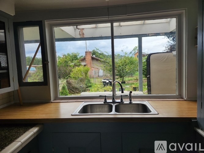 A kitchen with a sink and a window overlooking a garden.