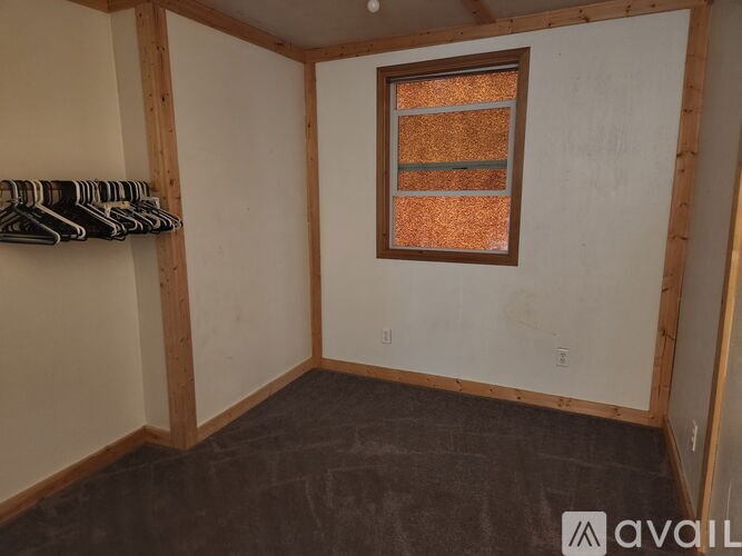 A room with a window and a coat rack.